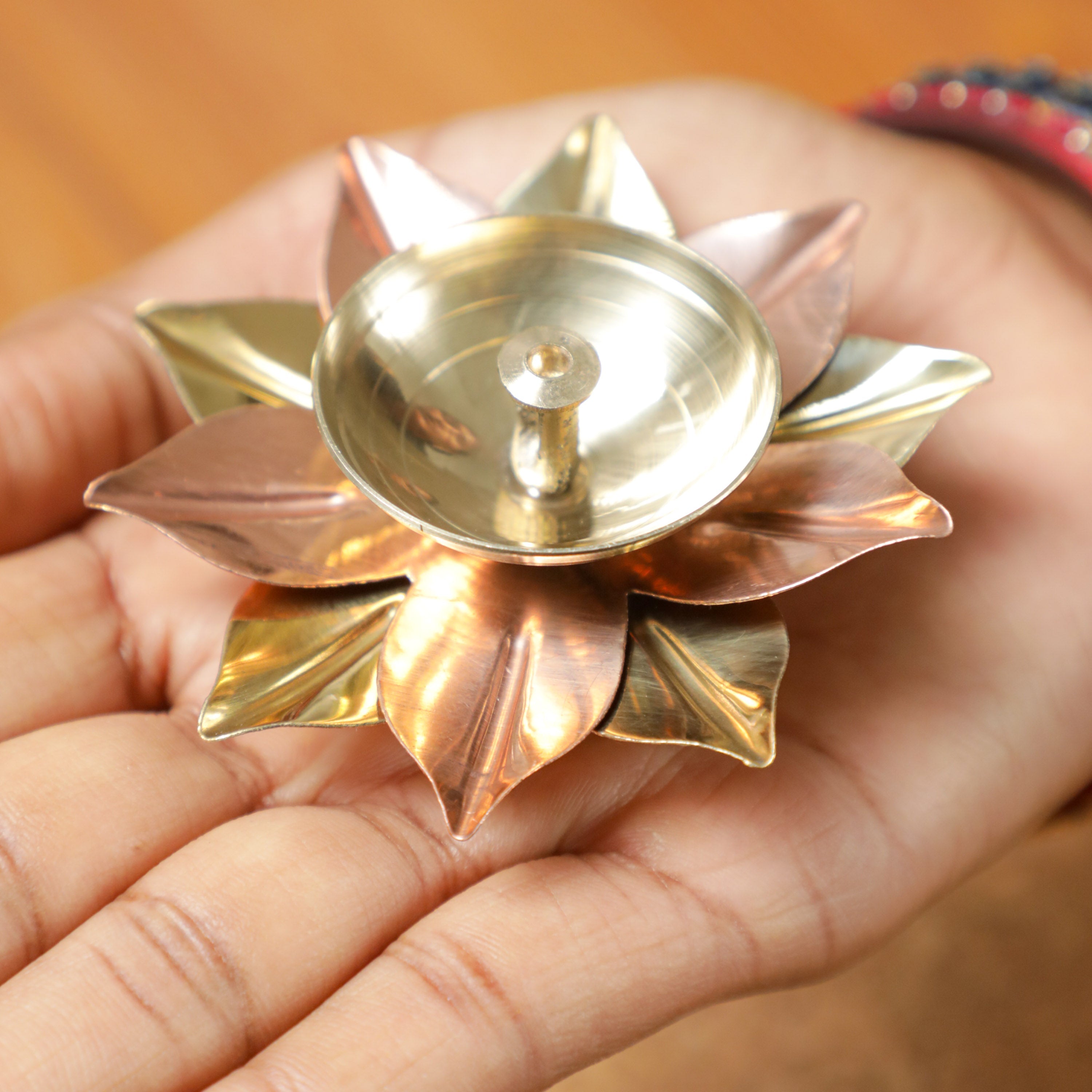 holding a brass diya in a hand